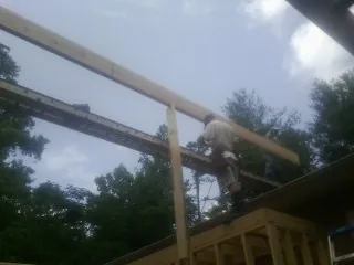 Carpenter setting a ridge beam over a new addition frame — Ice Dam Removal by Roofing Brothers in Hasty