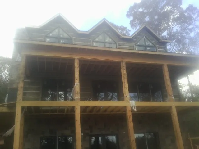 Dormers and porch framing on a large log home under construction — Roof Coating work by our crew in Hasty