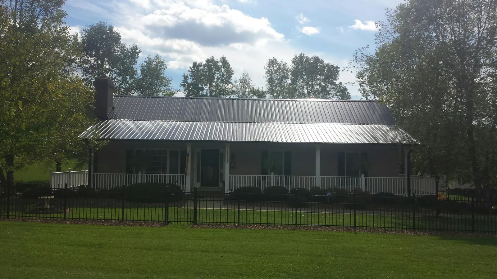 Gray metal roof on a brick ranch with a full width front porch — Gutter Guard Installation work by our crew in Hasty