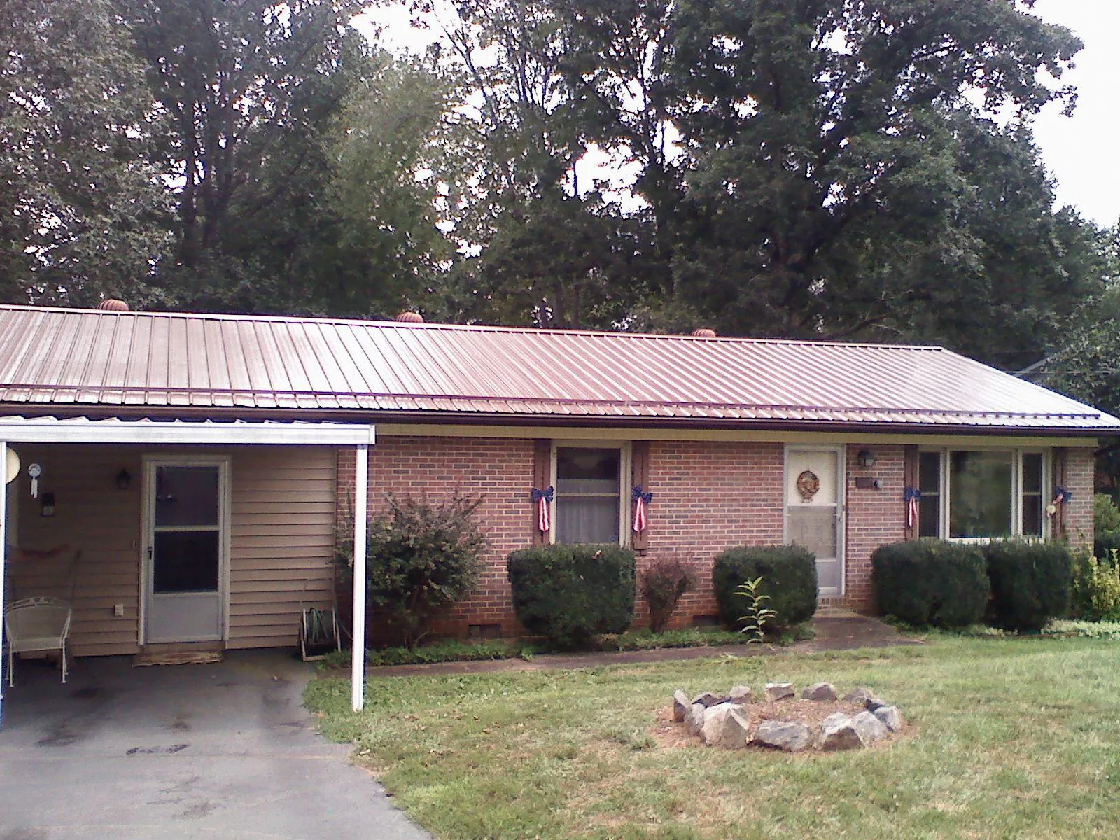 Bronze metal roof and carport on a brick ranch home — Roof Repair work by our crew in Hasty